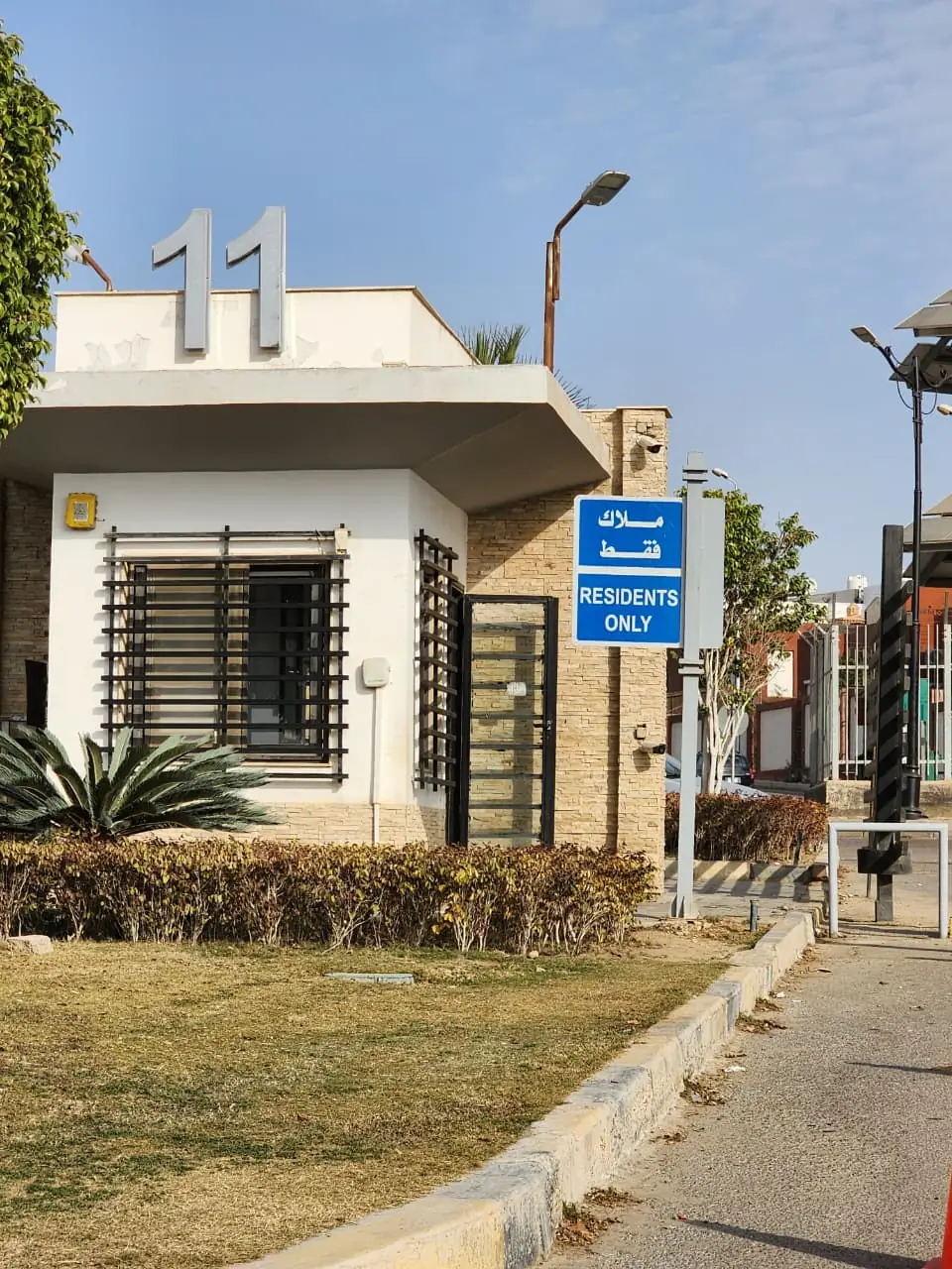 Bilingual residents-only directional sign and 3D block numerals at a compound gatehouse