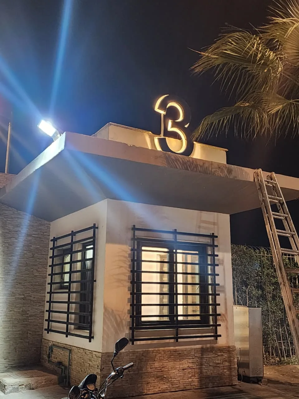 Illuminated 3D block numerals lit at night above a compound gatehouse