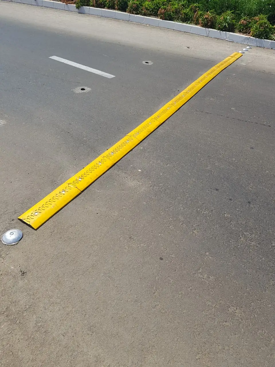 A long yellow lane divider strip installed along an asphalt road